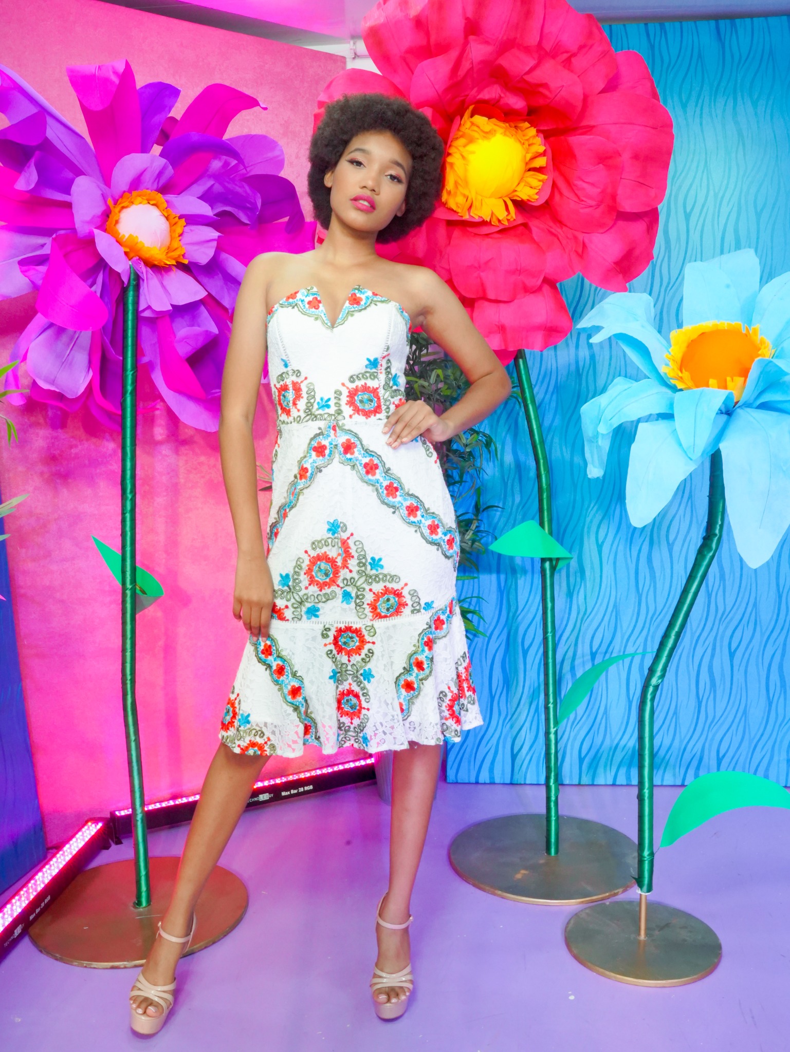 Modelo posando con vestido floral en una escenografía colorida